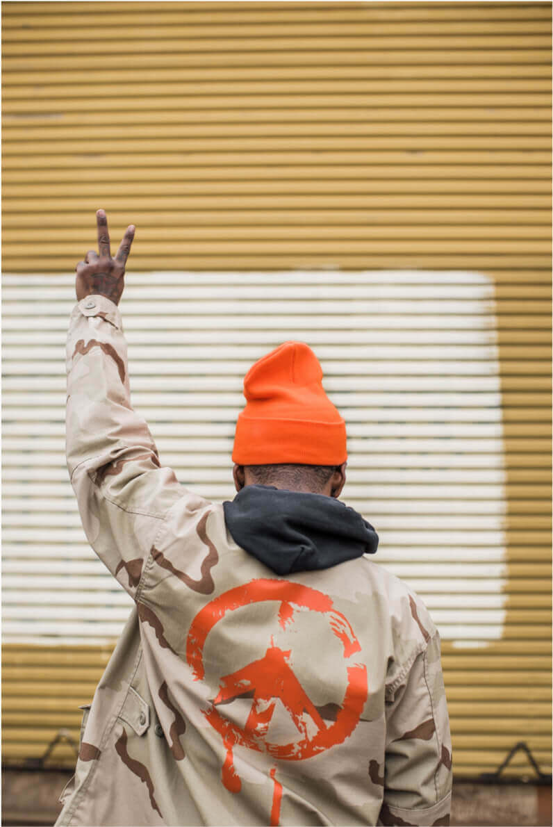a black man facing away from the camera holding a peace sign in the air.