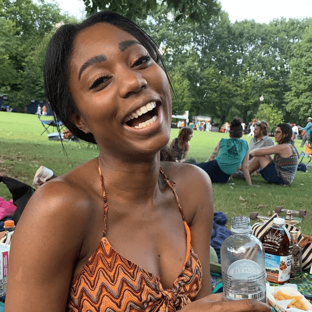 Alicia at a picnic laughing in an orange tie top