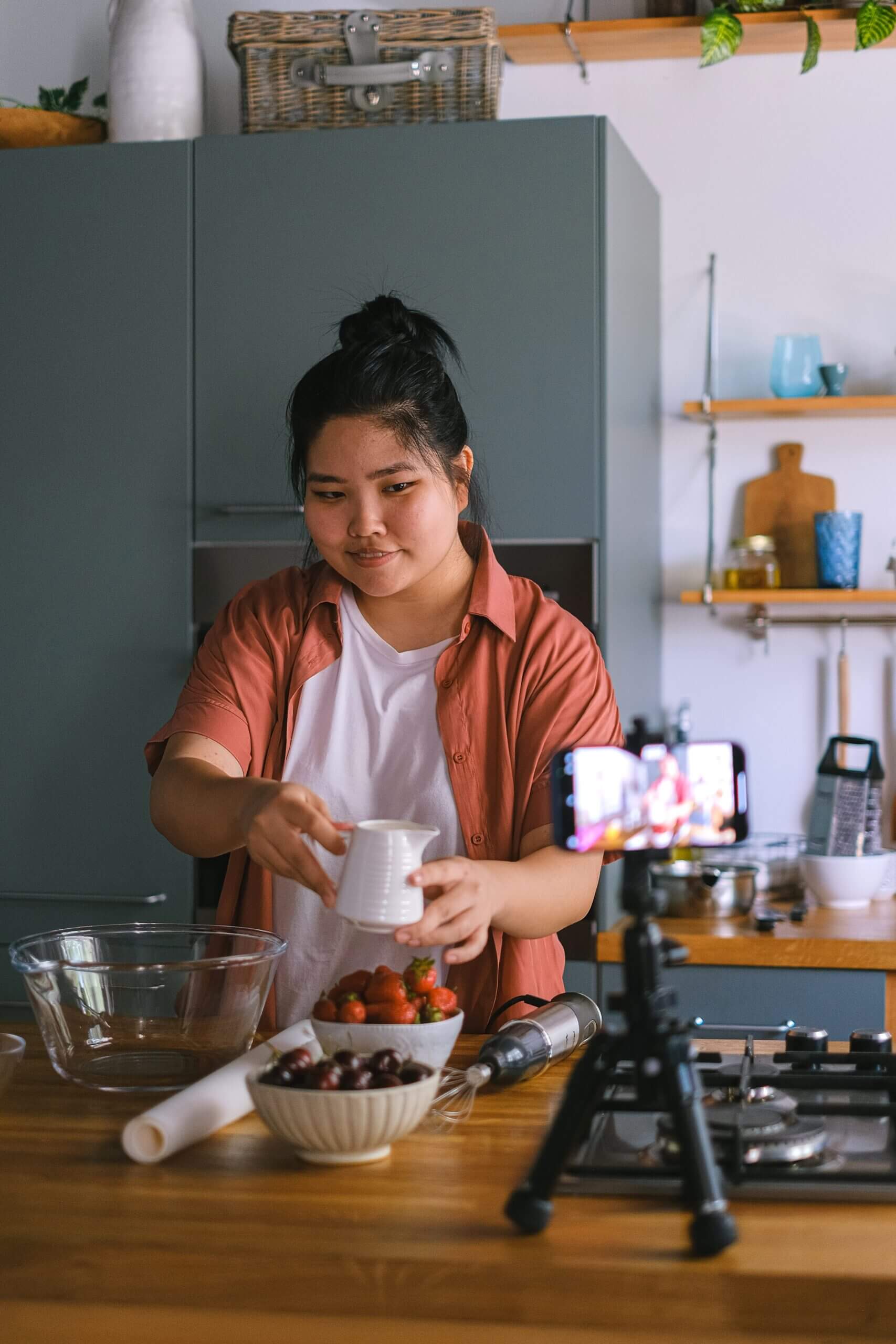 an asian woman with her phone propped up in a phone stand cooking